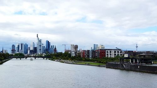 View of city at waterfront against cloudy sky