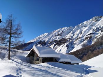 Scenic view of snow covered mountains against blue sky