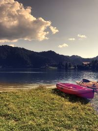 Boats moored on lake against sky during sunset