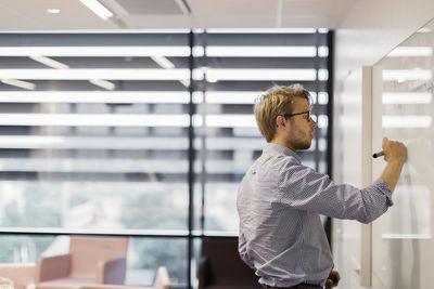 Businessman writing on whiteboard in office