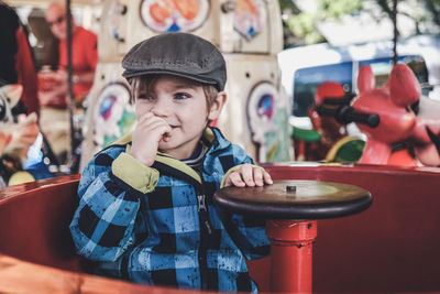 Cute boy sitting in ride at park