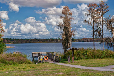 Bench by lake against sky