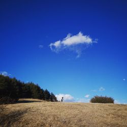 Man standing on landscape against blue sky