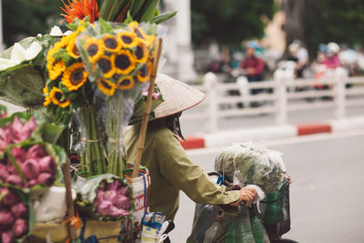 Rear view of man selling flowers on street