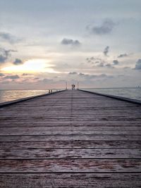 Pier over sea against sky during sunset