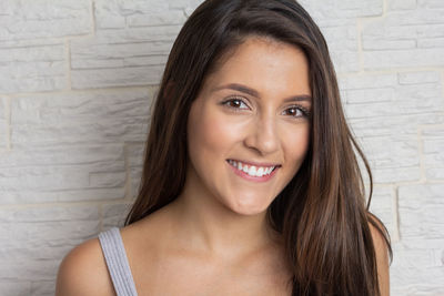 Portrait of a smiling young woman against wall