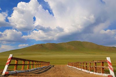 Empty road leading towards mountains against cloudy sky