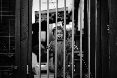 Portrait of crying boy standing by gate