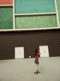 Full length of woman standing outside house