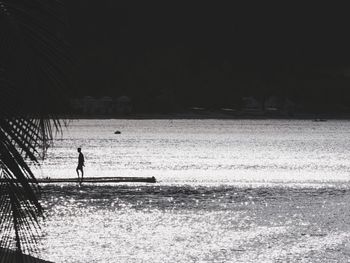 Silhouette man standing at beach against sky