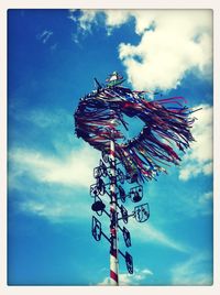 Low angle view of ferris wheel against cloudy sky