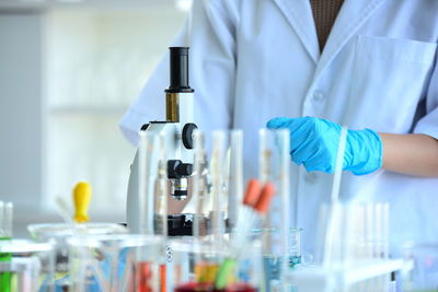 Midsection of scientist standing by microscope at laboratory