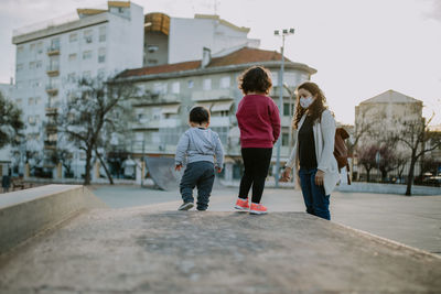 Mother wearing mask with kids against building