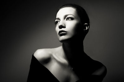 Serious young woman looking away against wall