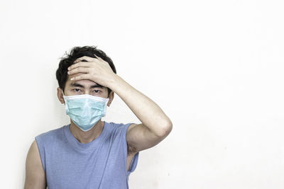 Portrait of man covering face against white background