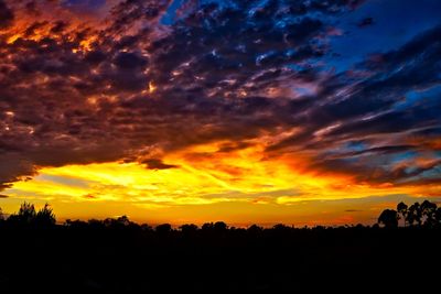 Silhouette landscape against dramatic sky during sunset