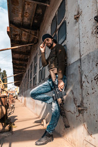 Full length of young man standing against wall in city