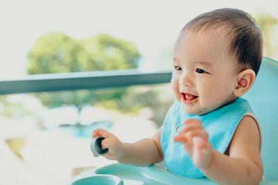 Close-up of cute baby boy looking away while sitting on high-chair