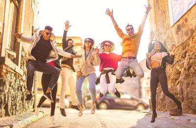 Cheerful friends jumping on road in city