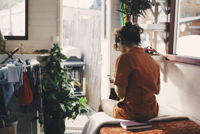 Rear view of woman sitting on bed in houseboat