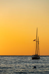 Sailboat sailing on sea against sky during sunset