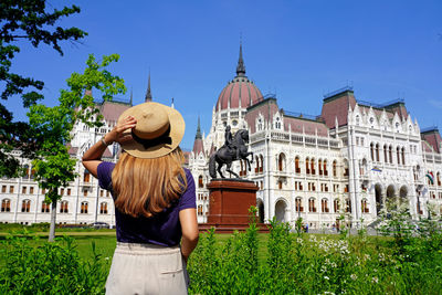 Back view of traveler girl enjoying view of hungarian parliament building in budapest, hungary