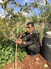 Man holding plants against trees