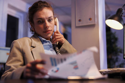 Young woman using mobile phone at table