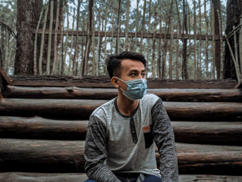 Portrait of young man standing against trees in forest
