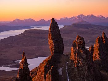 Rock formations by sea against sky during sunset