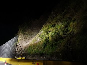 Low angle view of bridge by buildings against sky at night