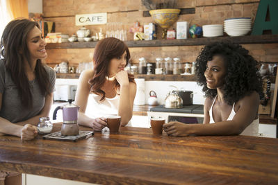 Female friends drinking coffee and enjoying in kitchen at home