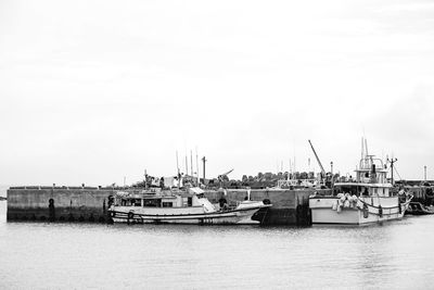 Boats moored at harbor against clear sky