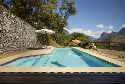 Full length of man jumping in swimming pool at tourist resort