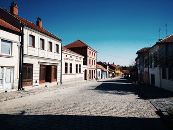 Footpath amidst buildings against blue sky