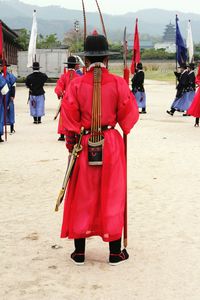 Rear view of men wearing traditional clothing standing outdoors