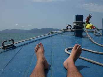 Low section of man on boat in sea against sky