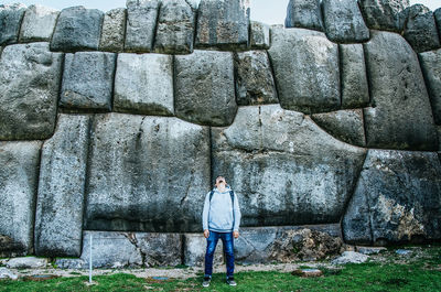 Full length of man standing against stone wall