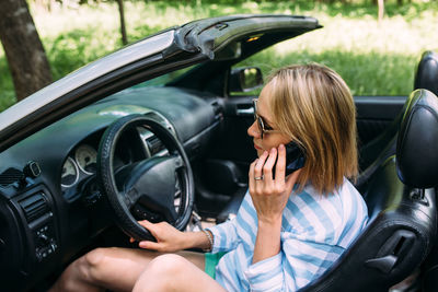 A woman is driving a convertible car. summer road trip to nature