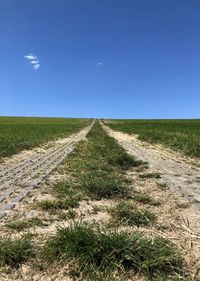 Road amidst field against clear sky