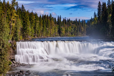 Scenic view of waterfall in forest against sky