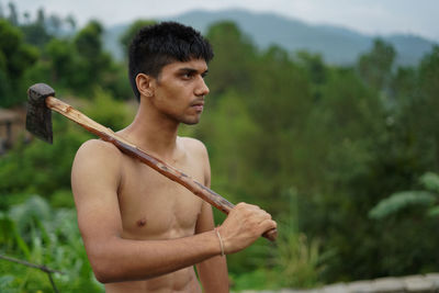 Young man looking away while standing on land
