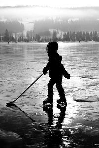  shadow of ice hockey kid standing on a frozen lake