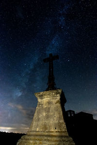 Low angle view of cross on building against sky at night