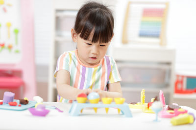 Portrait of cute girl playing with toys at home