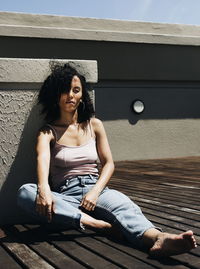 Mid adult woman sitting by wall