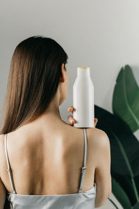 Midsection of woman holding bottle against white background