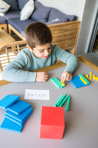 Little boy using the base 10 method to do addition at home