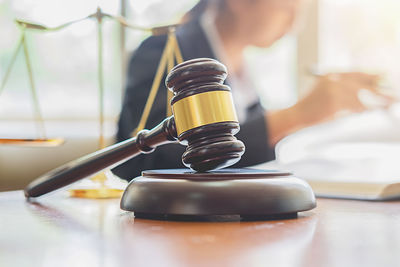 Close-up of gavel on table with female lawyer in background at office