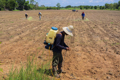 Thai farmer spraying insecticide in rice field, checking the jam spray device